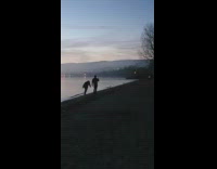 Two men silly dance on the shore at sundown