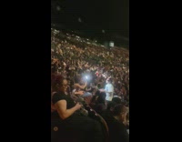 Man in white shirt and sunglasses poses in the crowd