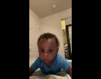 Baby lays on bed and says help in camera