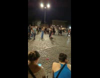 Woman in black dress dances to the performance of the man at the park