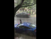 Lady washes car outside in rain 