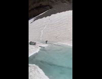 Guy snowboard cross over alpine lake pond