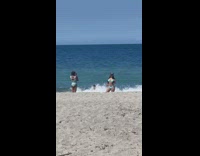 Little girl takes picture of woman in bikini at the beach