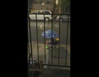 Guy holding umbrella grills food during storm 