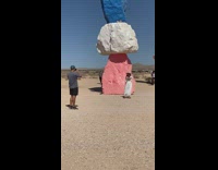 Girl white dress stacked large colorful rocks