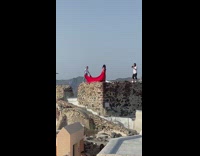 Assistant throw red dress skirt of woman Santorini