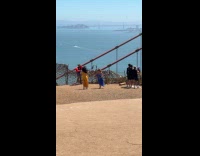 Woman in blue dress dances near bridge