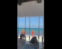 Lady in red bikini poses near beach outdoor dining area 