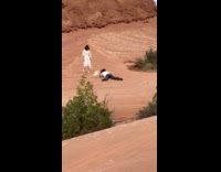 Woman white dress poses large rock behind