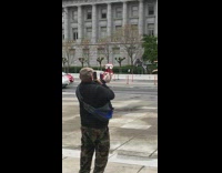 Guy holds small dog with one hand 