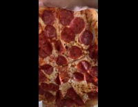 Man holding up whole pizza