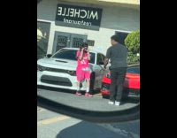 Man pink outfit poses beside white car