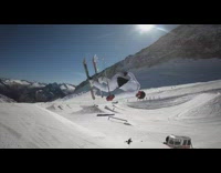 Skier does spin trick off ramp and lands backwards in snow