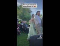 Groomsman walking down aisle smiles when he sees his girlfriend 