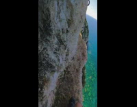 Guy walks narrow cliff ledge overlooking ocean 