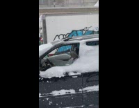 Car parked on the side of the road in snowstorm with windows down 
