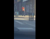 Guy wearing safety vest dances on sidewalk 