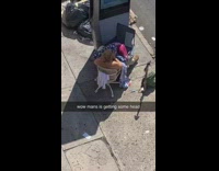 Guy sits chair girl blue blanket sidewalk 