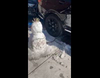 Snowman with chain beside parked car street