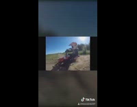 Red motorbike drifts on dirt road