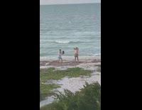 Guy hold hat against friend windy beach