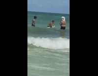 Man shirtless swim carry large yellow snake beach