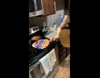 Girl with guitar trying to put frozen pizza into oven