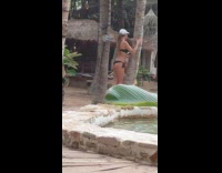 Woman hugs tree trunk takes picture in bikini