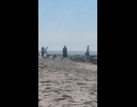 Woman dancing at beach filmed by crew