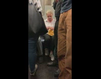 Woman knits yellow cloth, guy hols zombie hand on subway train