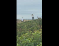 White shirt guy squats cliff edge windy