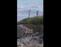 White shorts guy poses hill rock ocean 