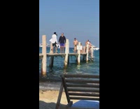 Guy holds bag orange shoes wood dock