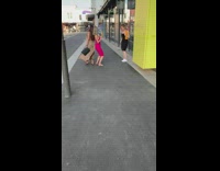 Two ladies dance on sidewalk 