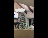 Guy in front of Christmas tree with woman pretends to RKO her