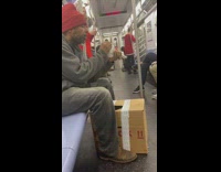 Guy inspects bird and reaches into cardboard box for another one on subway train