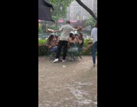 Guy standing in rain shielding girls from rain while they eat