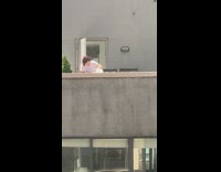 Woman grooming her pet rabbit on the roof of a neighboring building 
