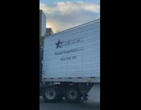 The back of a big rig is stuck in middle of street