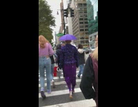 Woman in purple has an umbrella on her head