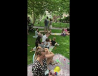 Guy performs childrens songs while two men practice battling nearby 
