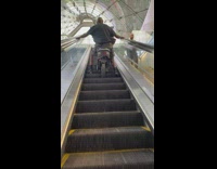 Man sitting on mini motorcycle going upstairs escalator 