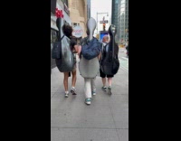 Three people wear large cello case on back