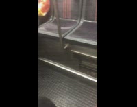 Barefoot man wearing rainbow tie dye jacket sits on a subway train