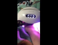 Grey cat paw under UV manicure lamp 