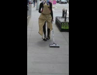 Guy walking down sidewalk drags vacuum behind 