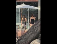 Two women in a black dress tiktok dance outside the shop