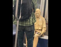 Living statue street performer sits still on subway 