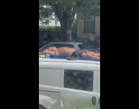 Guy tans on roof of white car