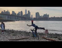 Guy on bike at beach balancing ball on head